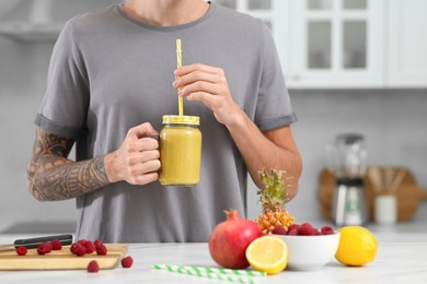 Photo of Man with delicious smoothie in kitchen, closeup