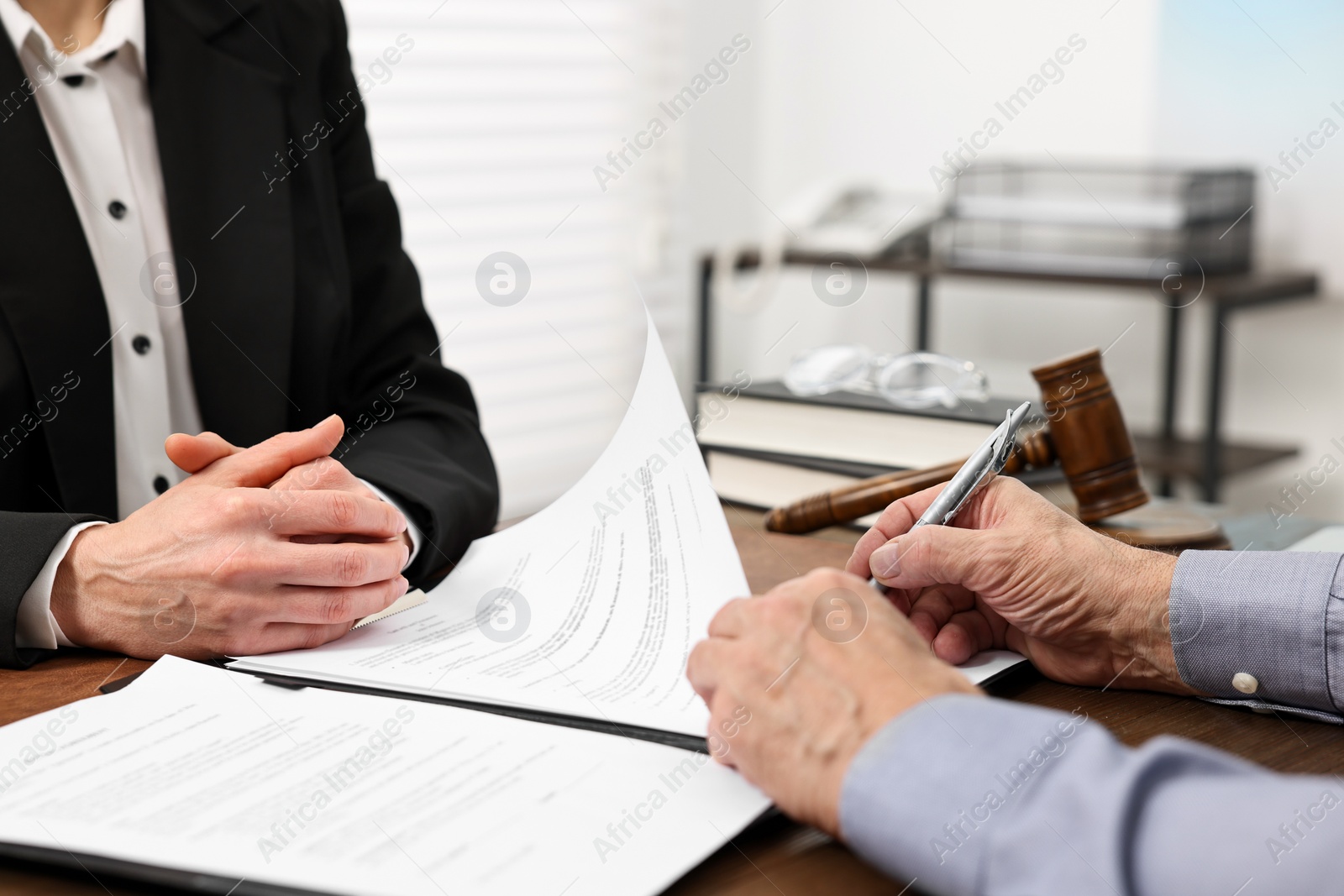 Photo of Senior man signing document in lawyer's office, closeup