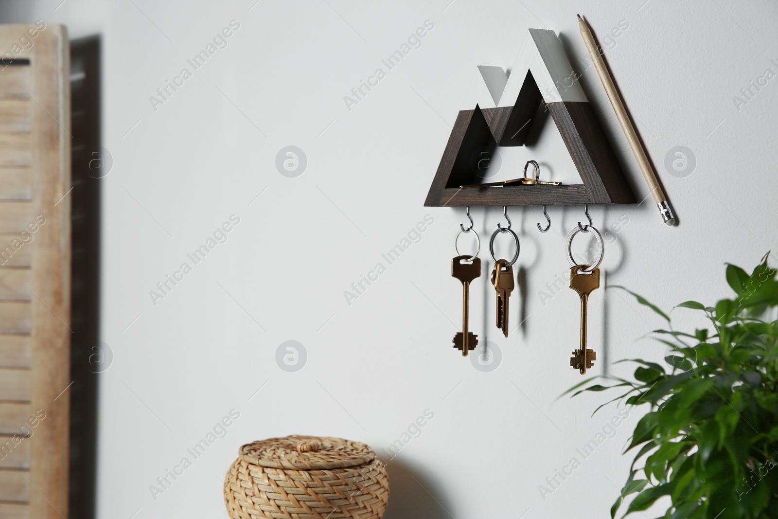 Photo of Wooden key holder on light wall indoors. Space for text