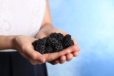 Photo of Woman holding fresh blackberry against color background. Space for text