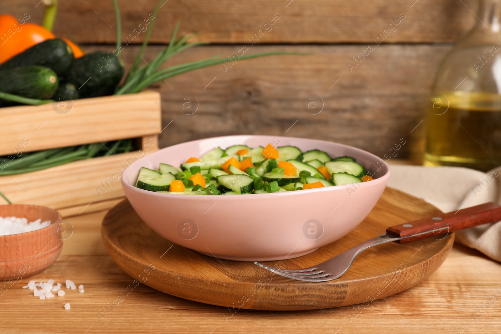 Photo of Tasty fresh salad with cucumber served on wooden table