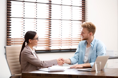 Photo of Female insurance agent shaking hands with client in office