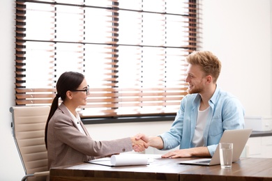 Female insurance agent shaking hands with client in office