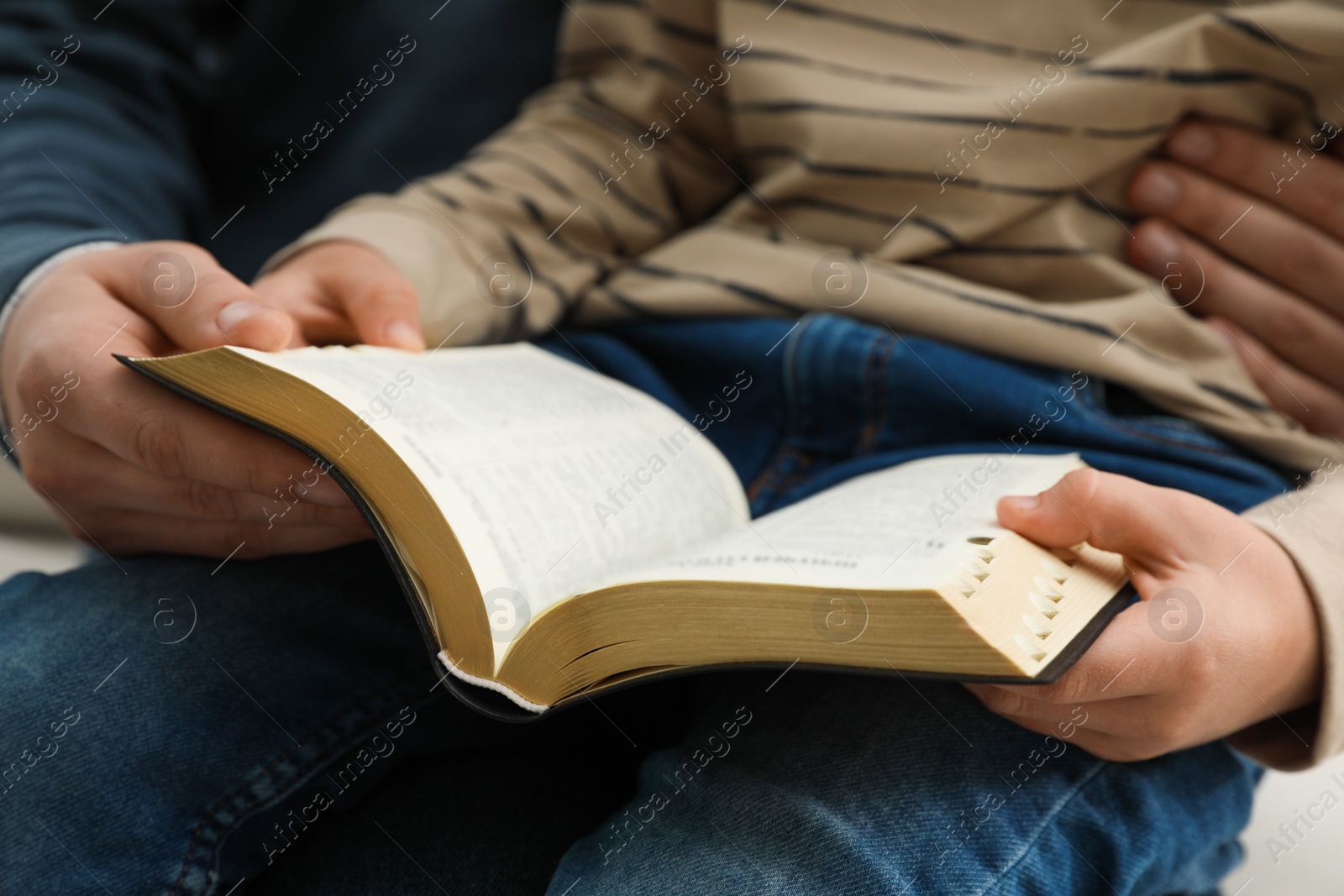 Photo of Boy and his godparent reading Bible together, closeup