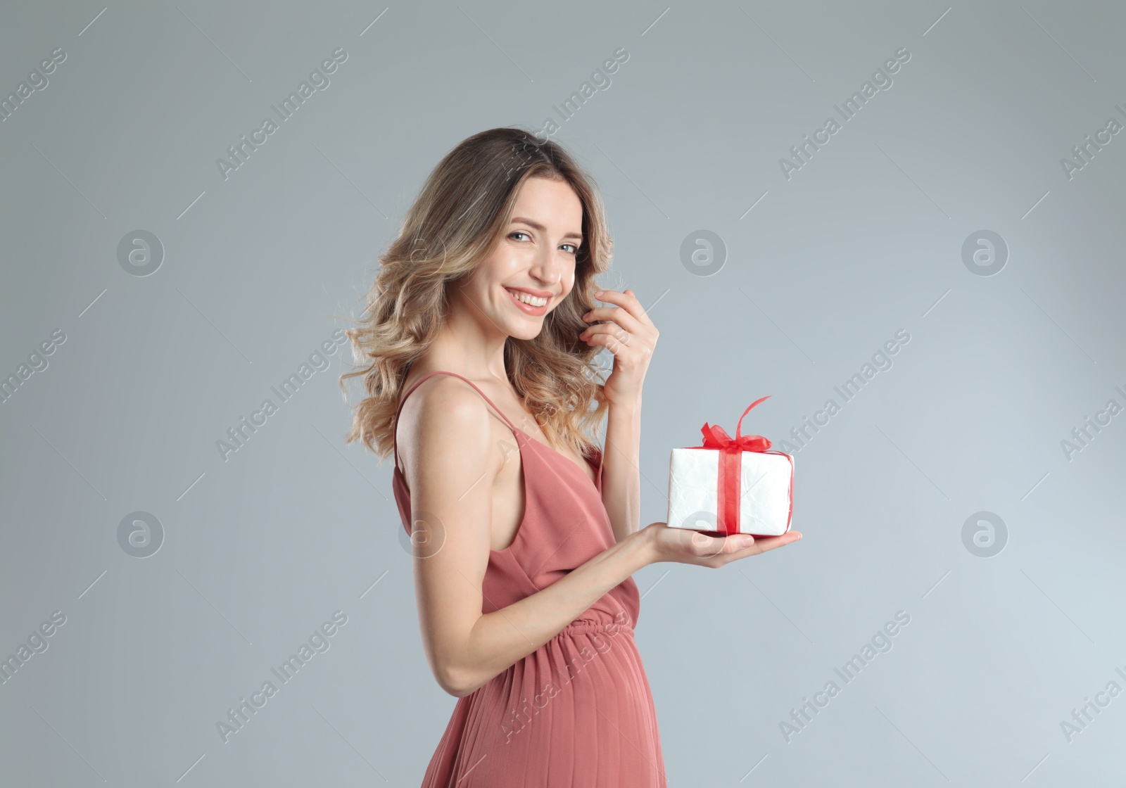 Photo of Beautiful young woman with Christmas present on light grey background