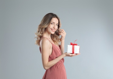 Photo of Beautiful young woman with Christmas present on light grey background