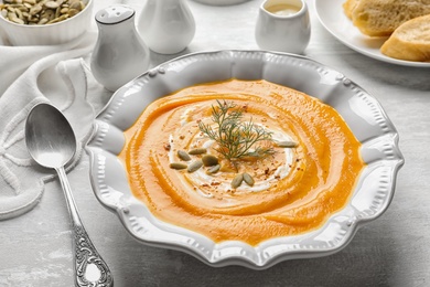 Plate with tasty pumpkin soup served on table