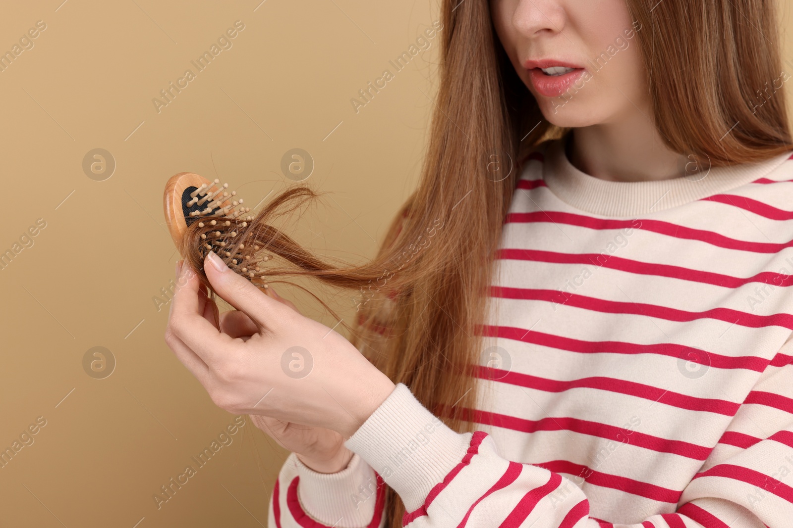 Photo of Woman brushing her hair on beige background, closeup. Alopecia problem