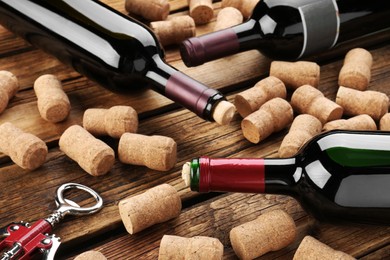 Bottles with wine, corkscrew and corks on wooden table