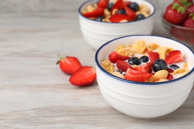 Bowl of tasty crispy corn flakes with milk and berries on wooden table. Space for text