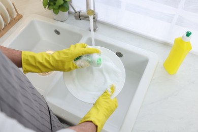 Photo of Man washing plate in kitchen sink, closeup