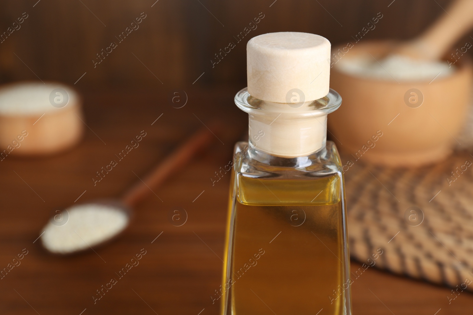 Photo of Fresh sesame oil in glass bottle on table, closeup. Space for text
