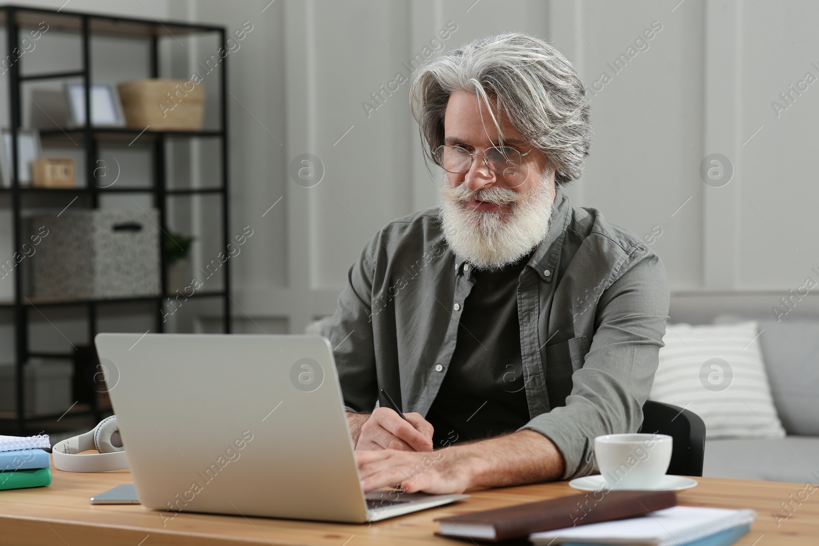 Photo of Middle aged man with laptop learning at table indoors