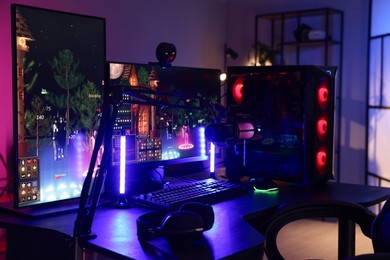 Photo of Playing video games. Stylish room interior with modern computer and gaming chair in neon lights