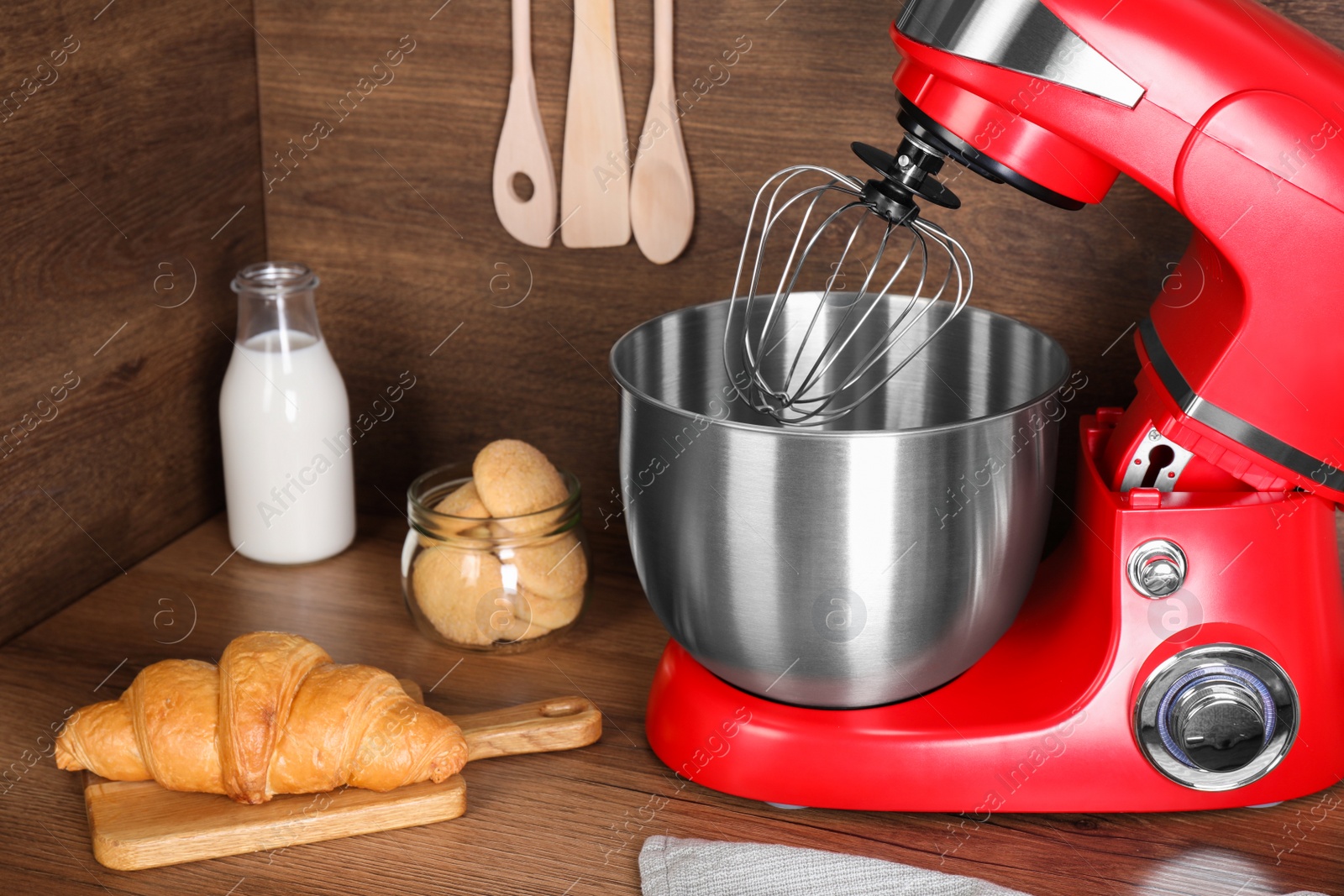 Photo of Modern red stand mixer, croissant and cookies on wooden table