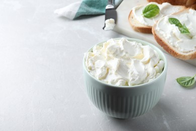 Photo of Bowl of tasty cream cheese on grey table. Space for text