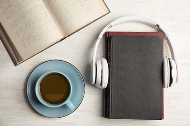 Photo of Books, coffee and headphones on white wooden table, flat lay