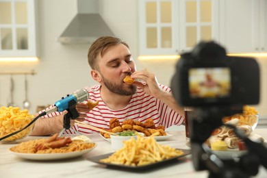 Photo of Food blogger recording eating show on camera in kitchen. Mukbang vlog