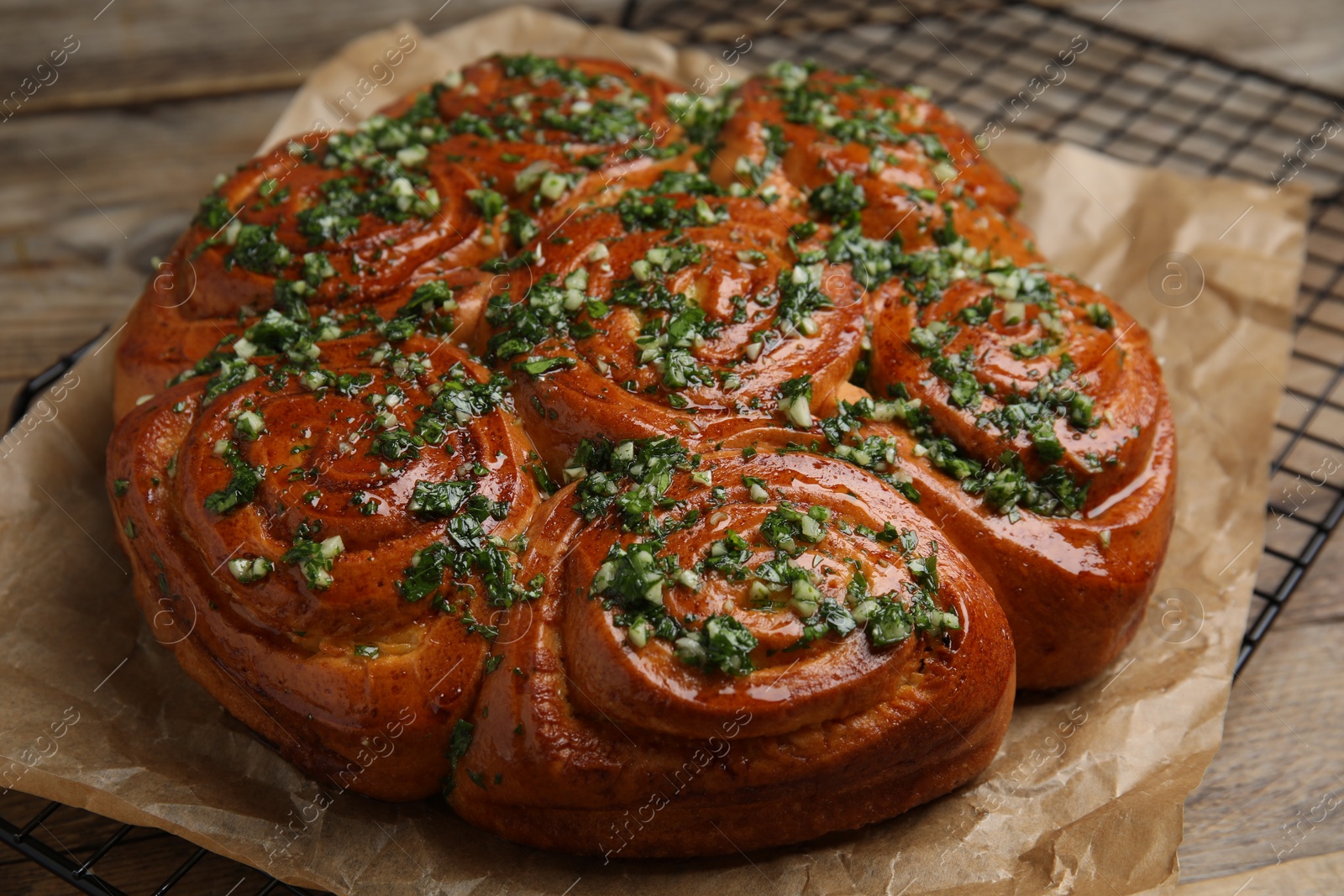 Photo of Traditional Ukrainian garlic bread with herbs (Pampushky) on wooden table, closeup