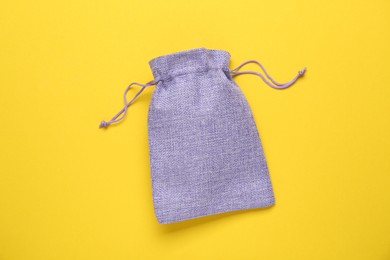 Photo of Violet burlap bag on yellow background, top view