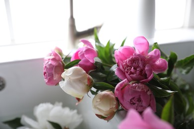 Photo of Bunch of beautiful peonies in kitchen sink, closeup