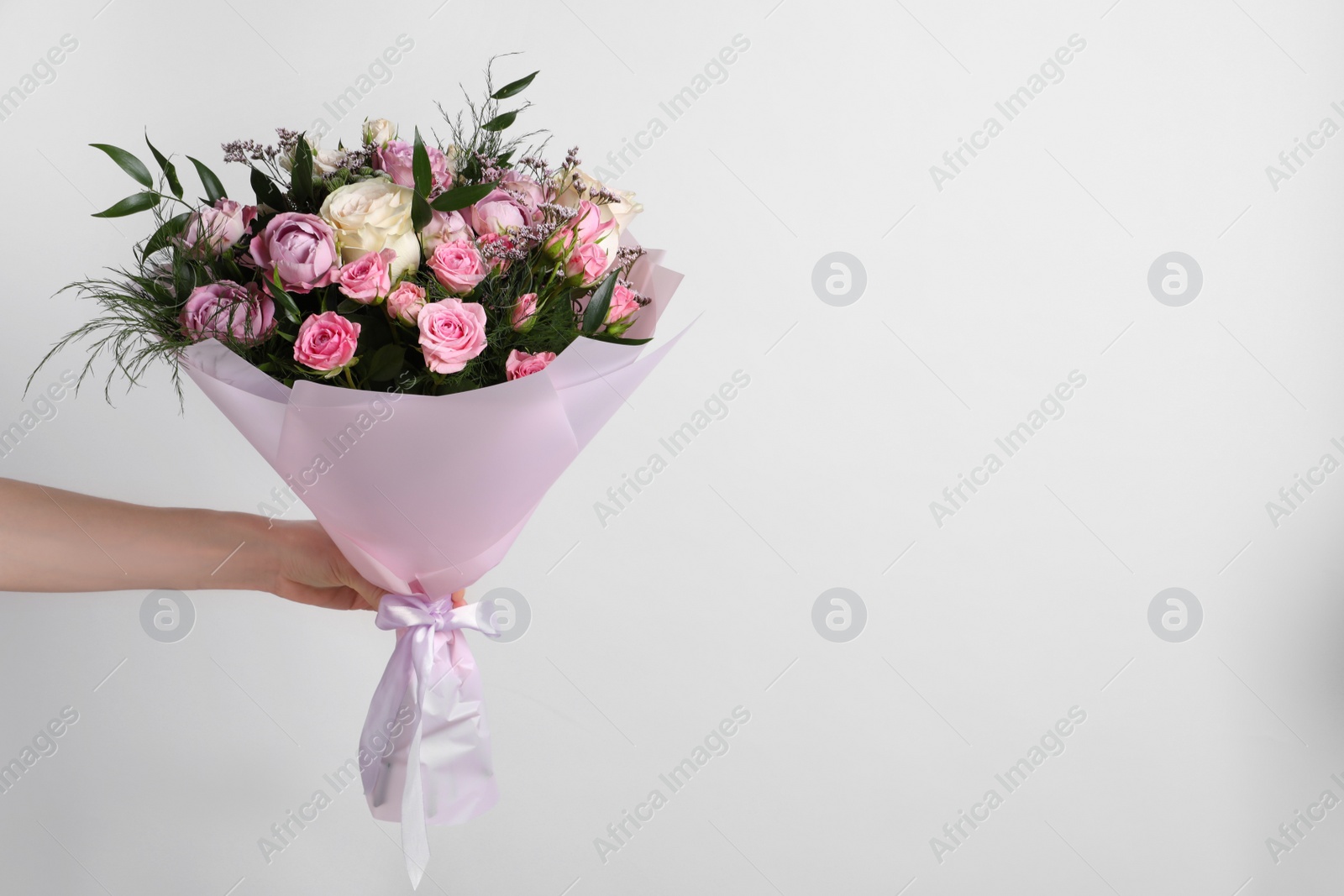 Photo of Woman with bouquet of beautiful roses on light background, closeup. Space for text