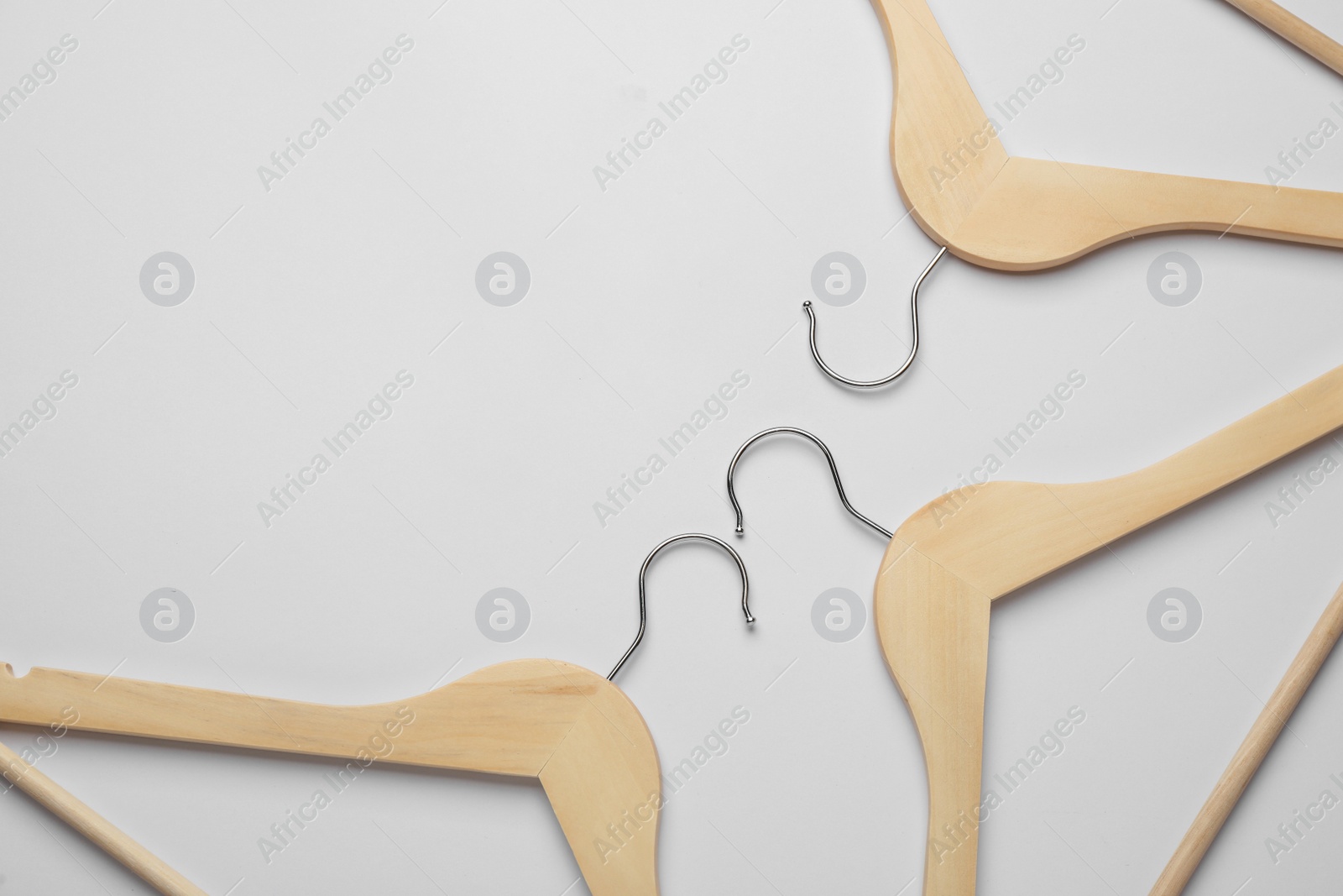 Photo of Empty wooden hangers on light grey background, flat lay. Space for text