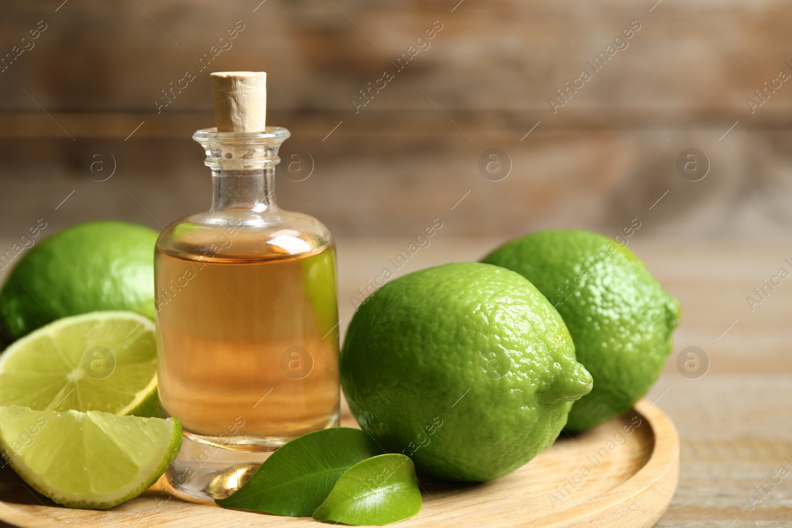 Photo of Lime essential oil and citrus fruits on wooden table, closeup