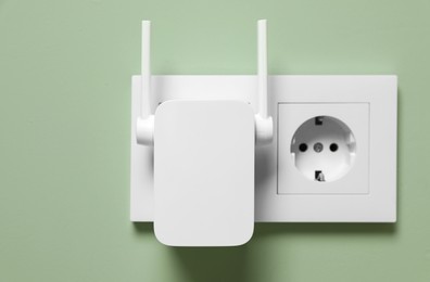 Photo of Wireless Wi-Fi repeater on light green wall indoors