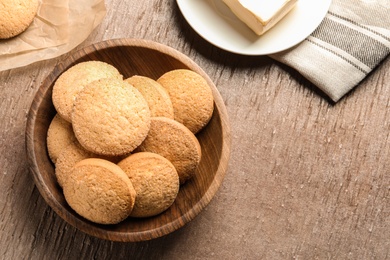 Photo of Bowl with Danish butter cookies on wooden background, top view. Space for text