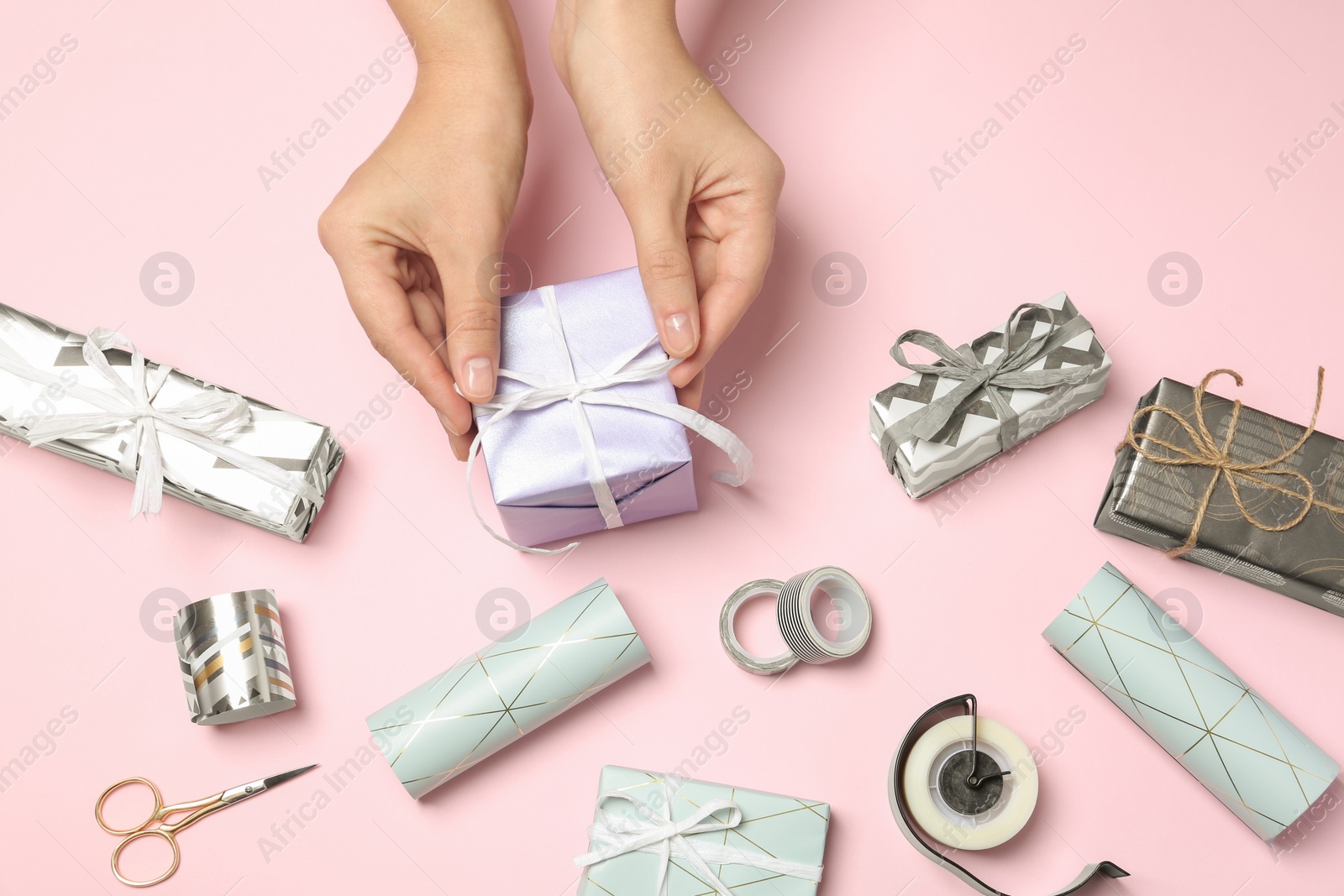 Photo of Woman with gift box and tools for decor on color background, view from above