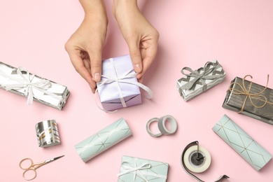 Woman with gift box and tools for decor on color background, view from above