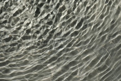 Photo of Rippled surface of clear water on light grey textured background, top view