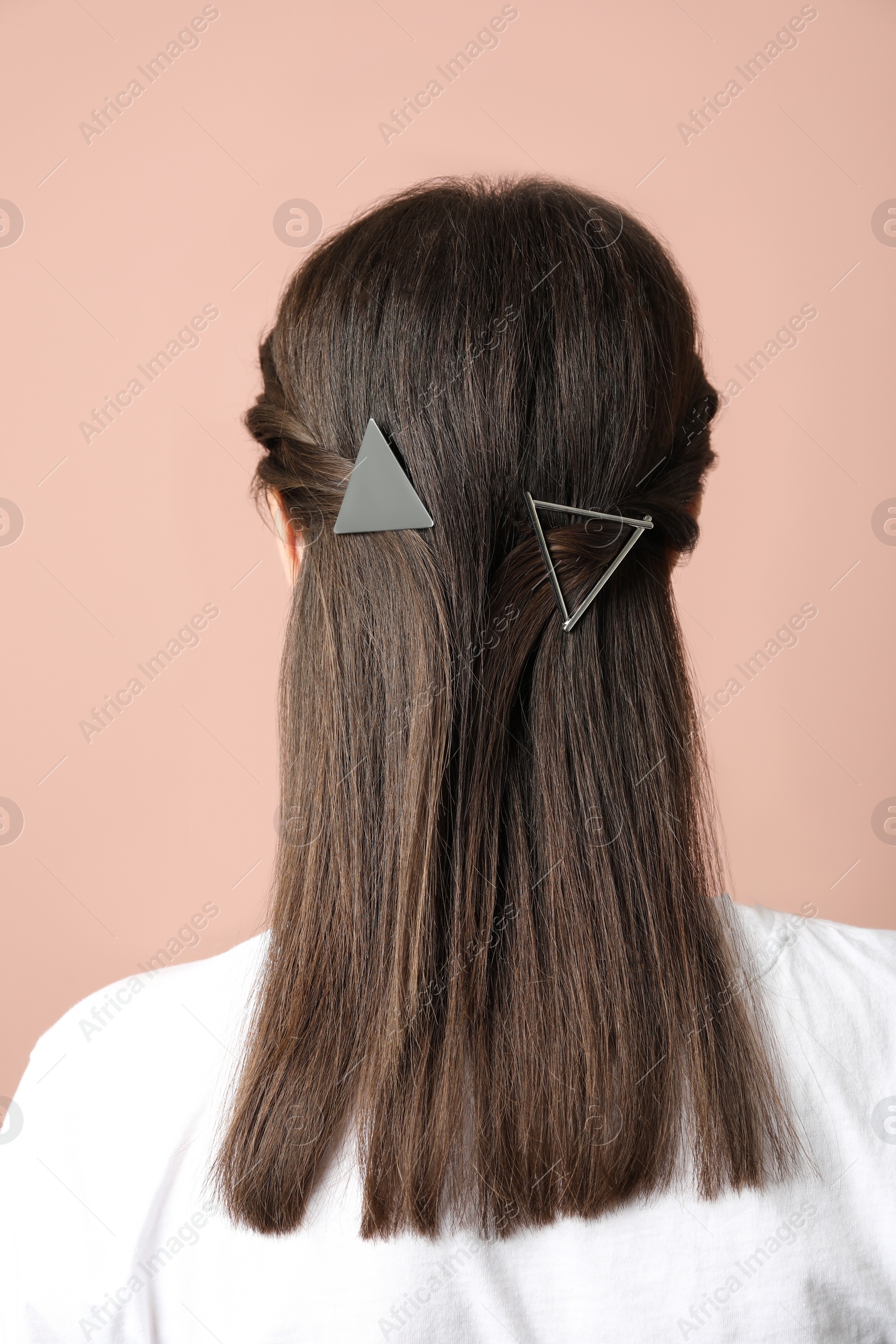 Photo of Young woman with beautiful hair clips on pink background, back view