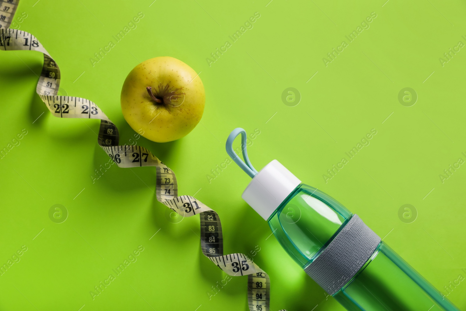 Photo of Measuring tape, bottle with water and apple on light green background, flat lay. Weight control concept