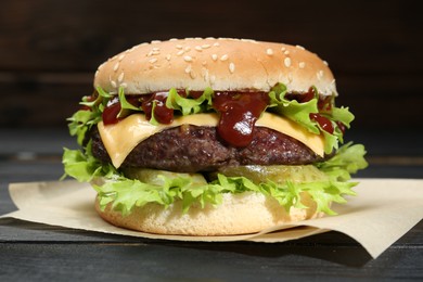 Photo of Burger with delicious patty on black wooden table, closeup