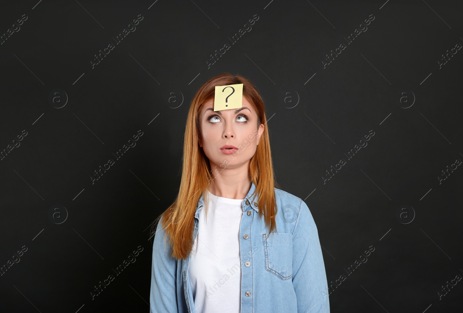 Photo of Emotional woman with question mark sticker on forehead against black background