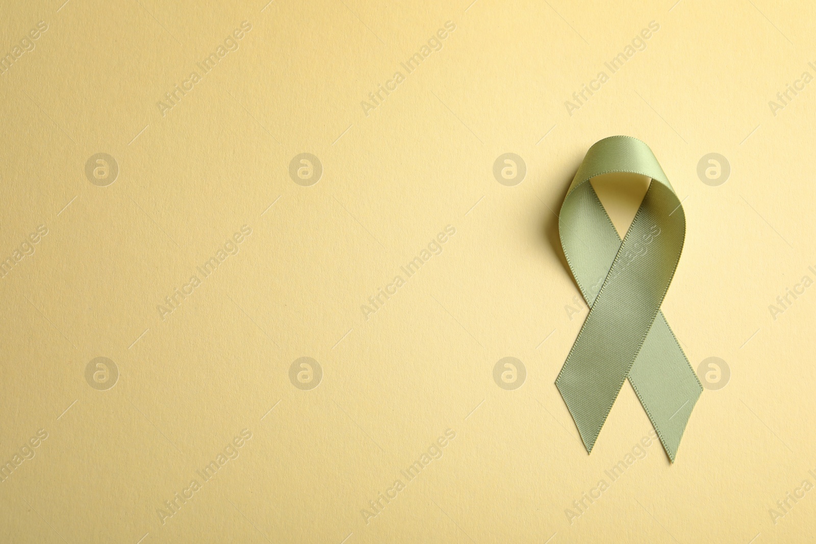 Photo of Green ribbon on color background, top view. Cancer awareness