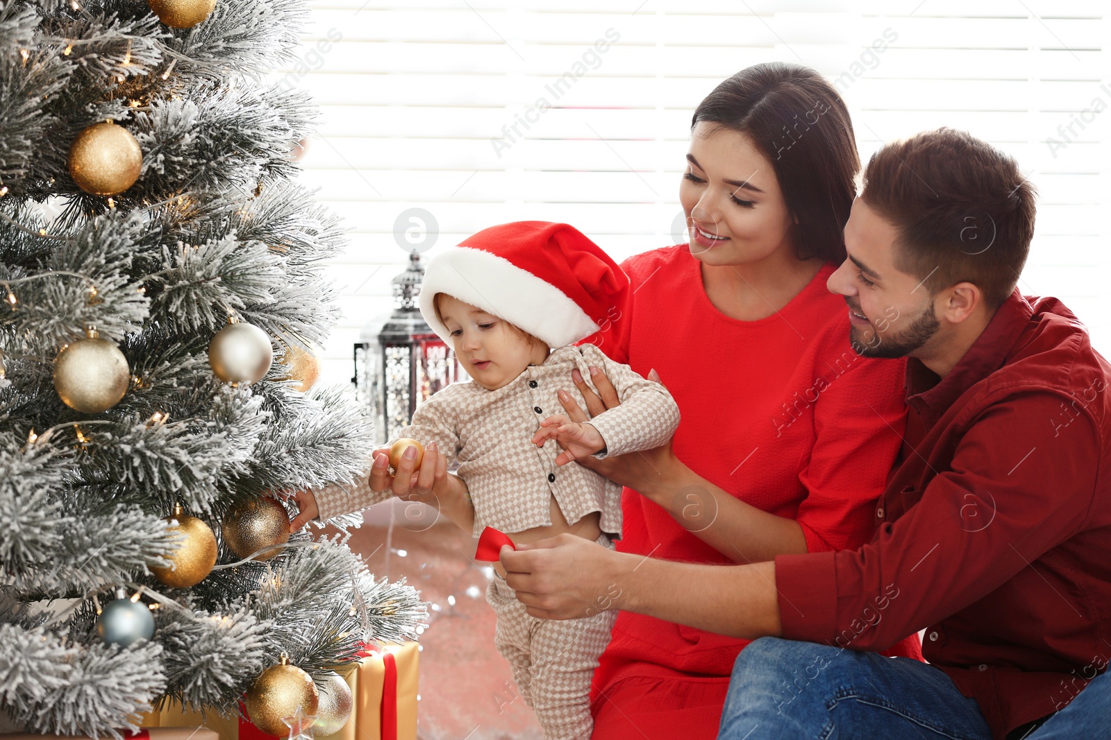 Photo of Happy family with cute baby near Christmas tree at home