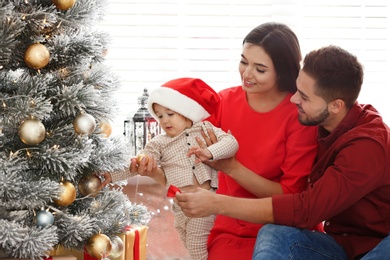 Happy family with cute baby near Christmas tree at home