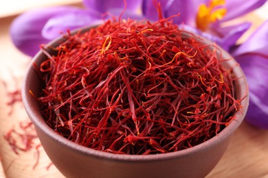 Photo of Dried saffron and crocus flowers on wooden tray, closeup