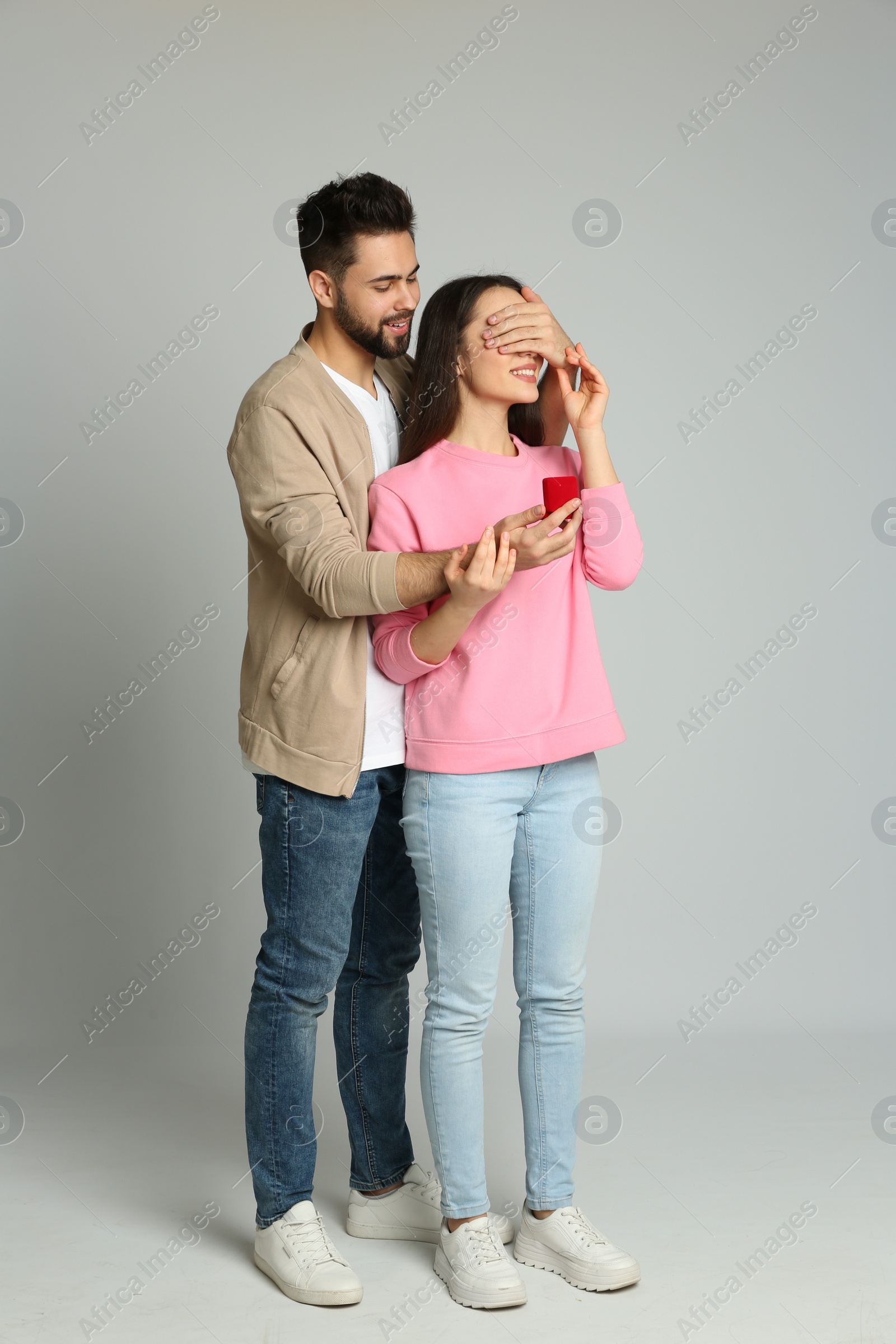 Photo of Man with engagement ring making marriage proposal to girlfriend on light grey background