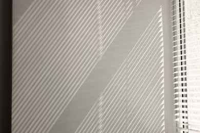Shadow from window and blinds on beige wall indoors
