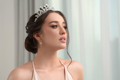 Photo of Beautiful young woman wearing luxurious tiara indoors, space for text