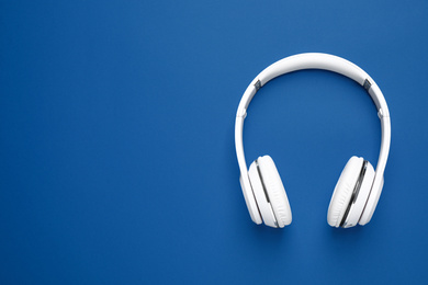 Photo of Headphones on bright background, top view with space for text. Color of the year 2020 (Classic blue)