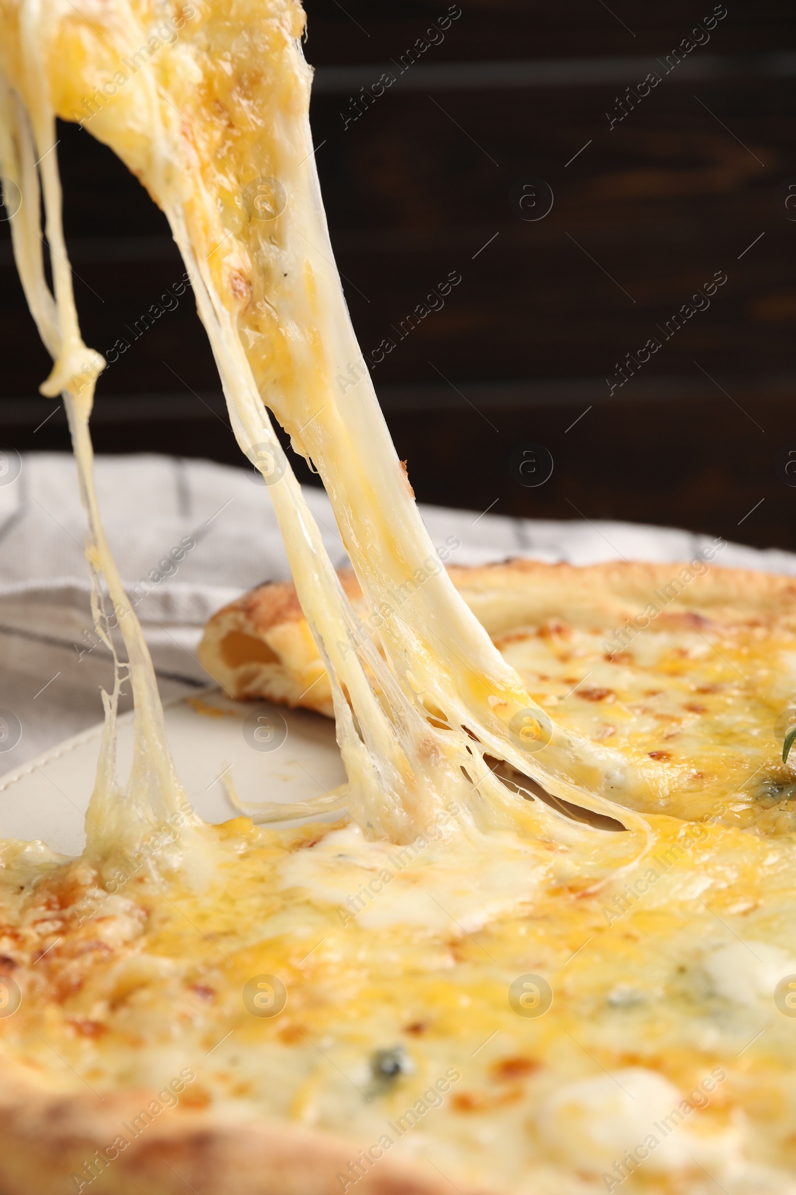 Photo of Taking piece of delicious cheese pizza at table, closeup