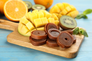 Photo of Composition with delicious fruit leather rolls on light blue wooden table