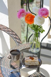 Photo of Tasty dessert, cup of fresh aromatic coffee and flowers on glass table outdoors