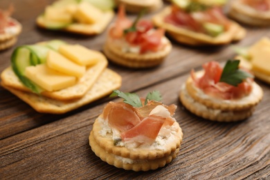Different snacks with salted crackers on wooden table, closeup