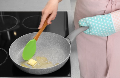 Photo of Woman stirring butter in frying pan on electric stove, closeup